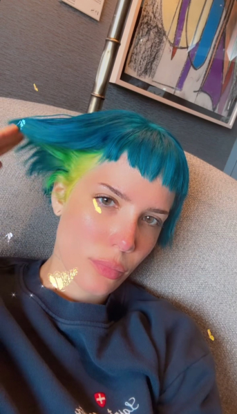 Halsey lifting her blue hair to show green and yellow underneath