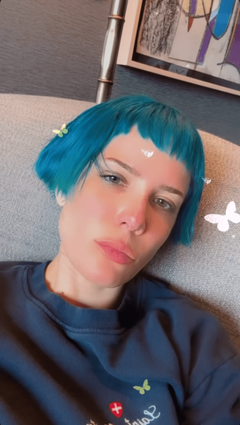 Halsey sitting on a couch with a turquoise bob hairstyle